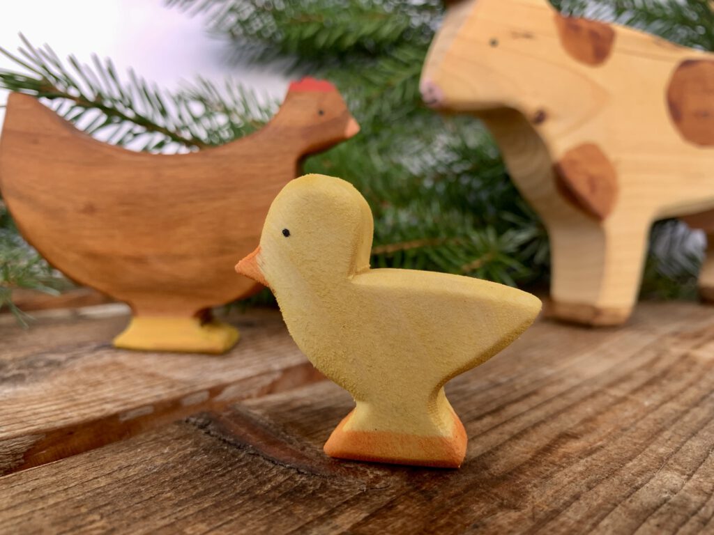 Sägefisch-Holzküken aus nachhaltigem Holzspielzeug aus Deutschland, im Vordergrund mit Henne und Kuh im Hintergrund als sinnvolles Weihnachtsgeschenk für Kleinkinder.
