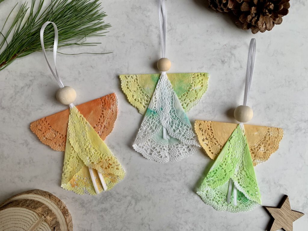 tortenspitzen-engel-selbstgemacht-weihnachtsdeko-mit-kindern.jpg Mehrere selbst gebastelte Weihnachtsengel aus Tortenspitze als süße DIY Deko für die Adventszeit. Schnelles Bastelprojekt für Kleinkinder