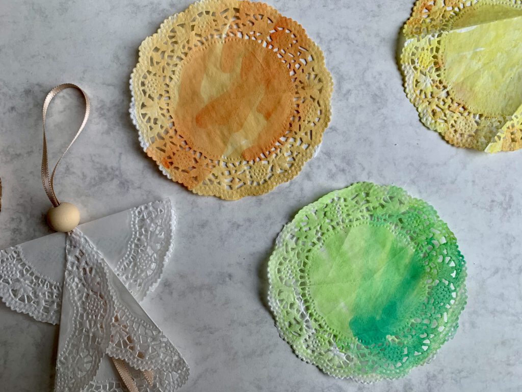 bemalte-tortenspitzen-kleinkind-wasserfarben-weihnachtsbasteln.jpg Mehrere bunte, mit Wasserfarben bemalte Tortenspitzen, die ein Kleinkind für Weihnachtsengel vorbereitet hat.