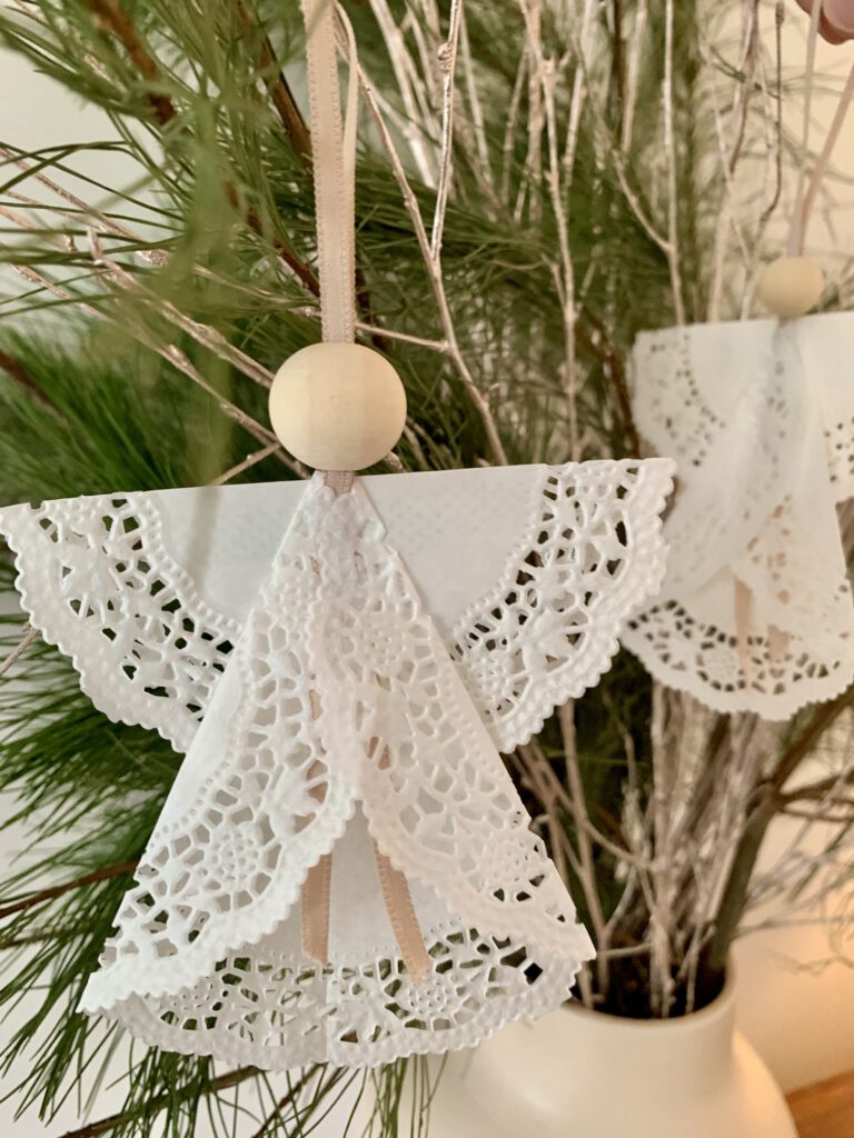 weihnachtsengel-tannengruen-adventsgesteck-basteln-mit-kindern.jpg Zwei Weihnachtsengel aus Tortenspitze hängen dekorativ an Tannengrün im Adventsgesteck. Schnelle Anleitung Weihnachtsengel falten.