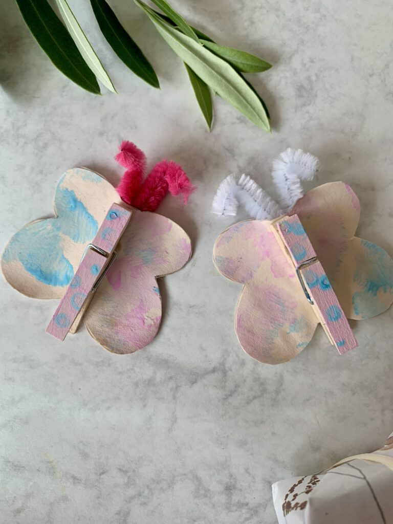 Schmetterlinge in Pastellfarben, gebastelt aus Wäscheklammern und Tonpapier als schöne Frühlingsdeko gebastelt mit Kleinkind.