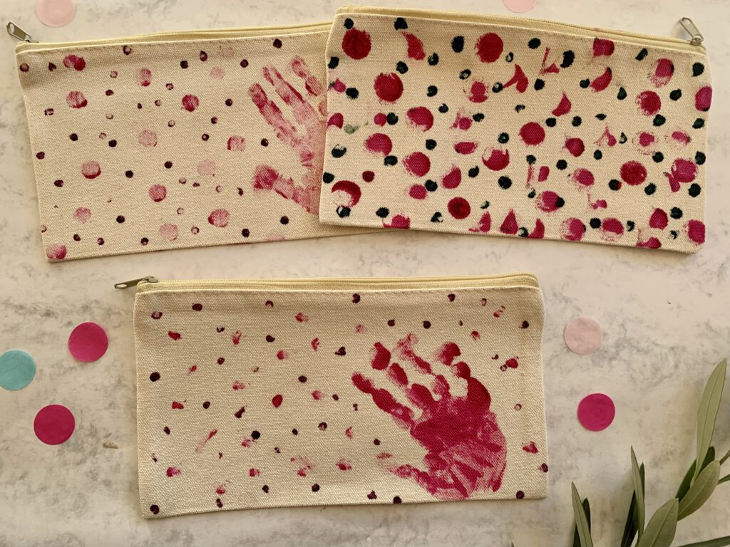 Mehrere selbst bemalte Kosmetiktäschchen mit Handabdruck als Geschenkidee für Oma und Familie