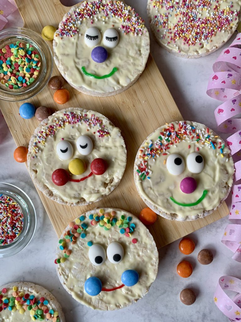 lustige-reiswaffel-gesichter-kinder Verschiedene lustige Reiswaffel Gesichter mit bunten Streuseln, Smarties und Luftschlangen. Einfache Rezeptidee für Fasching.