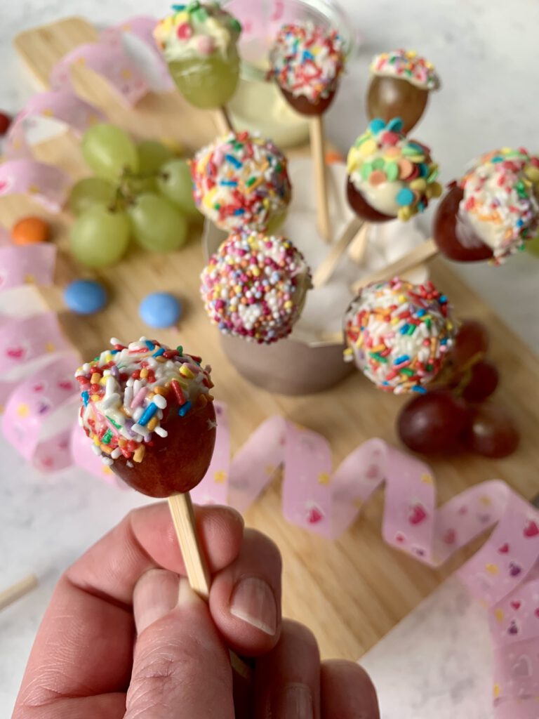 Konfetti-Trauben als schneller Fasching Snack für Kinder: Weintrauben mit weißer Schokolade, dekoriert mit bunten Zuckerstreuseln.