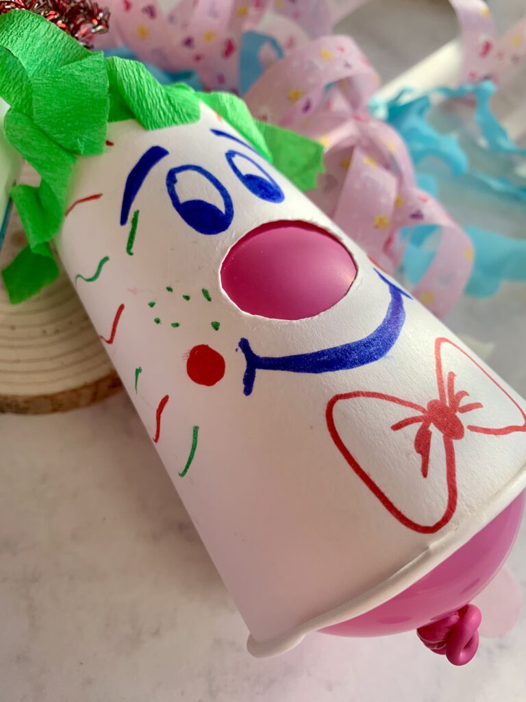 Detailaufnahme eines Pappbecher-Clowns mit grünem Krepppapier als Haare. Eine einfache Bastelidee für Fasching mit Kindern.