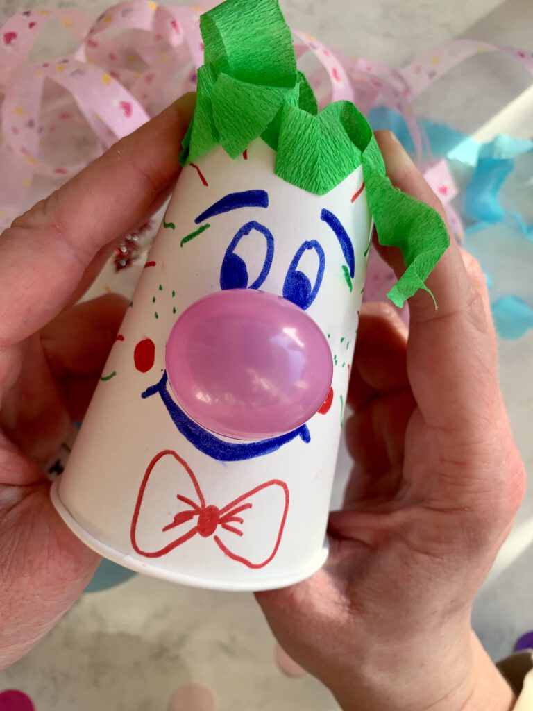 Clown mit Zaubernase beim Drücken, die Nase ploppt aus dem Pappbecher. Eine lustige Idee für Fasching mit Kindern.