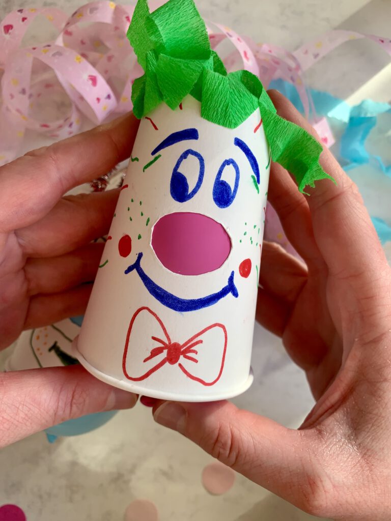 Ein selbst gebastelter Pappbecher-Clown wird in der Hand gehalten