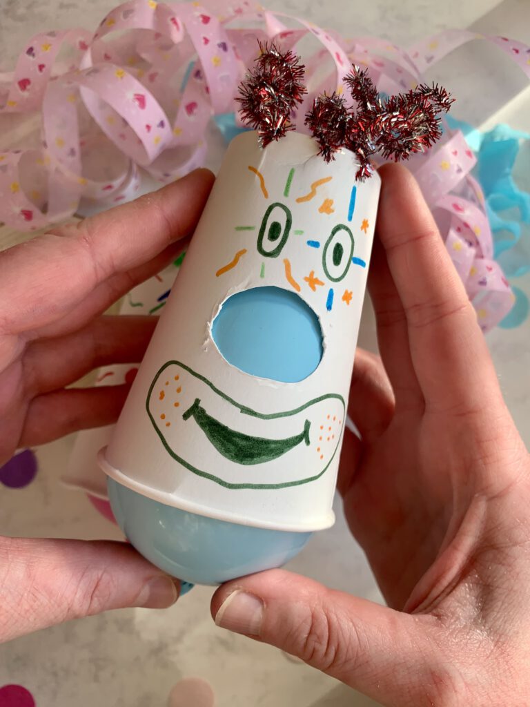 Pappbecher-Clown mit blauer Nase und Pfeifenputzer-Haaren wird gehalten