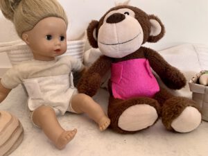 DIY Puppenwindel ohne Nähen an einer Puppe, daneben ein Kuschelaffe mit pinker Windel