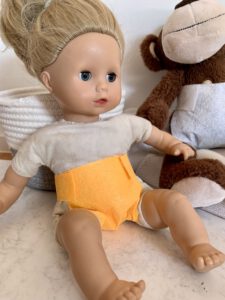 puppenwindel-diy-gelb-sitzend.jpg Sitzende Puppe mit gelber selbstgemachter Puppenwindel, daneben Kuschelaffe mit weißer Windel