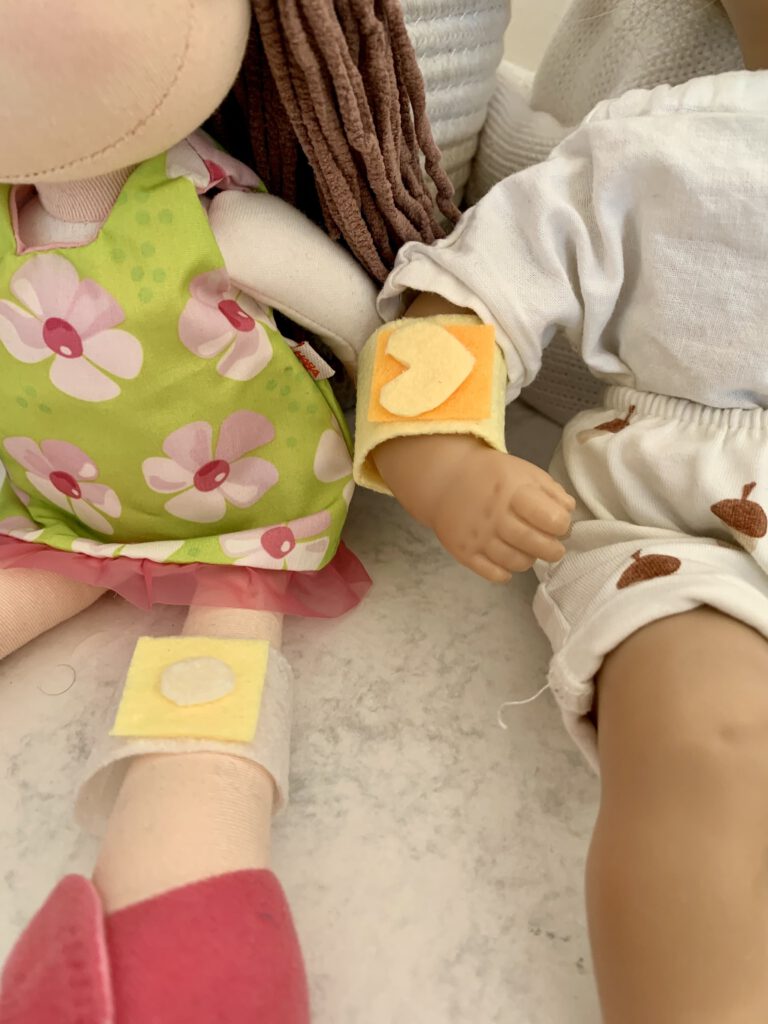 Zwei Puppen mit wiederverwendbaren Spielpflastern aus Filz beim Arzt-Rollenspiel