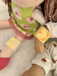 Selbstgemachte Puppenpflaster ohne Nähen an zwei Puppen im Kinderzimmer