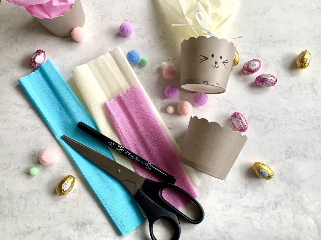 Material für ein kleines Ostergeschenk: Muffinförmchen, Krepppapier, Schnur, Kleber und Pompom