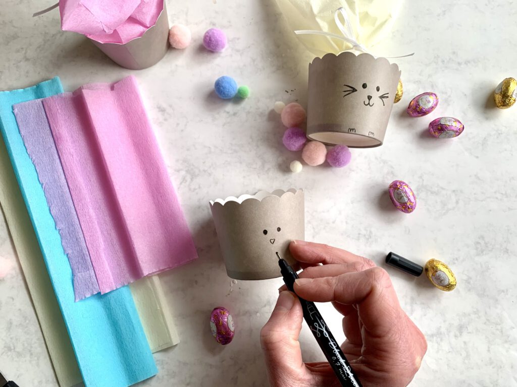 Hasengesicht wird auf ein Muffinförmchen für das Osterkörbchen gemalt. Ideal als kleines Geschenk oder Mitbringsel zu Ostern