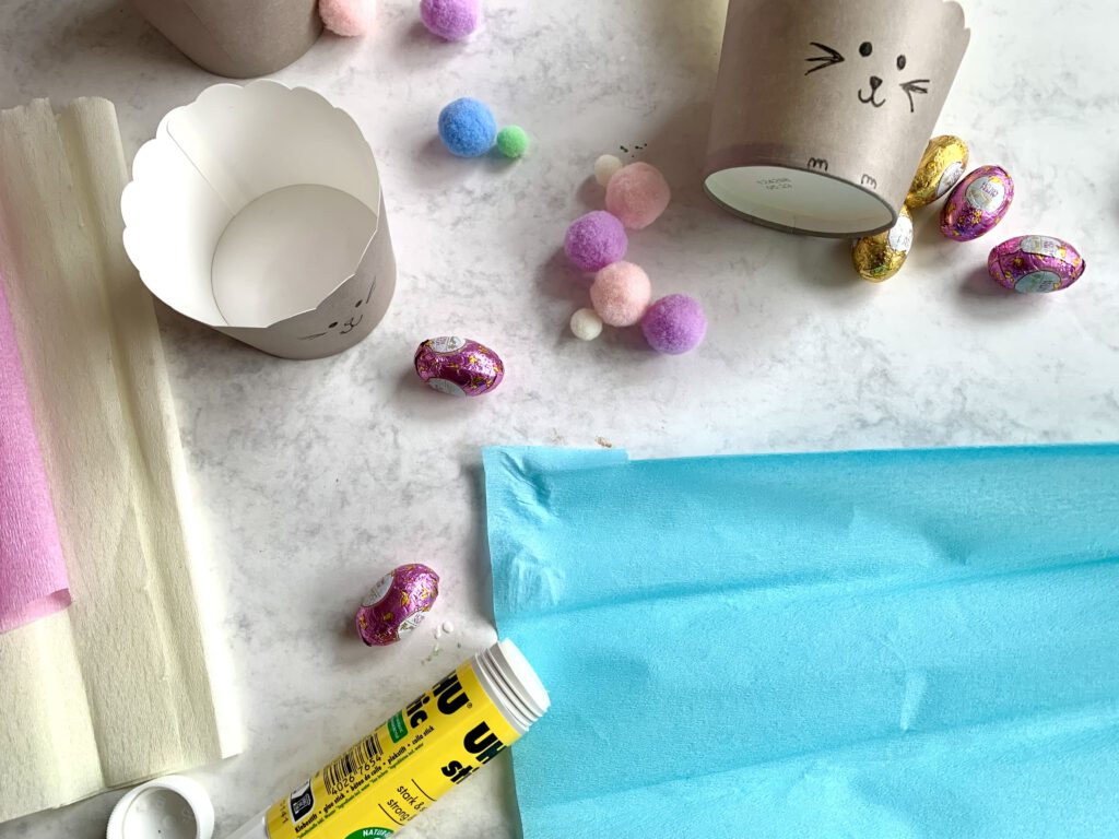 Kleber wird auf Krepppapier aufgetragen für ein selbstgemachtes Osterkörbchen