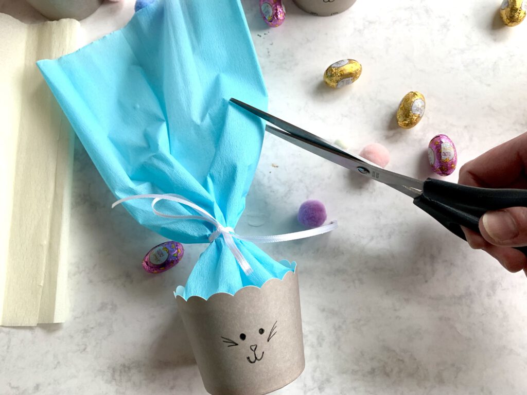 Hasenohren werden aus überstehendem Krepppapier für das Osterkörbchen ausgeschnitten