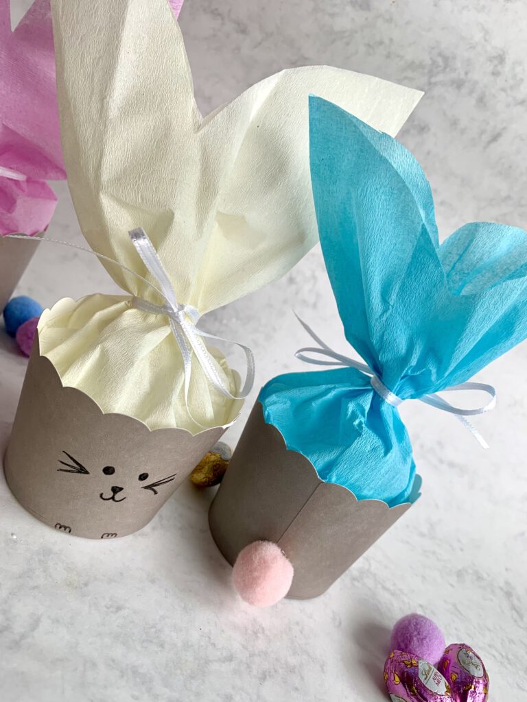 Beiges und blaues Osterkörbchen aus Muffinförmchen mit Hasenohren und Schleife