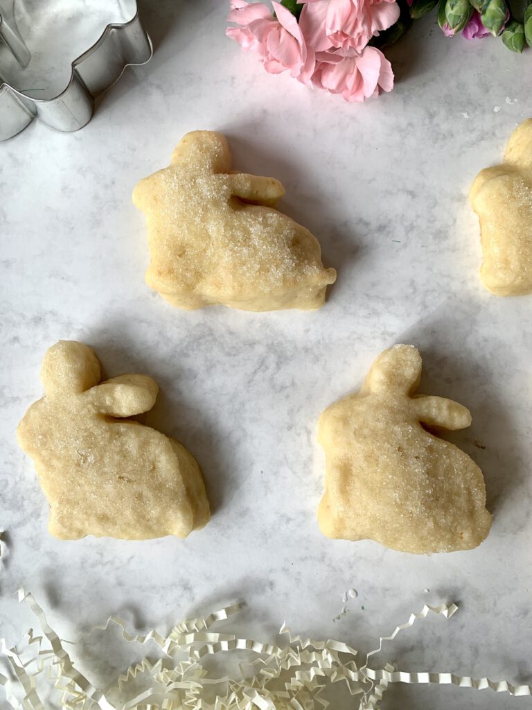 Vier goldbraune Quarkhasen ohne Hefe mit Frühlingsblumen und Ausstechformen – einfaches Osterrezept für Familien