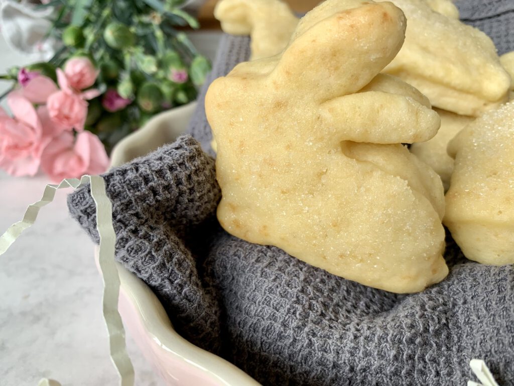 Osterhase aus Quark-Öl-Teig mit Frühlingsblumen im Hintergrund – einfache Osterbäckerei