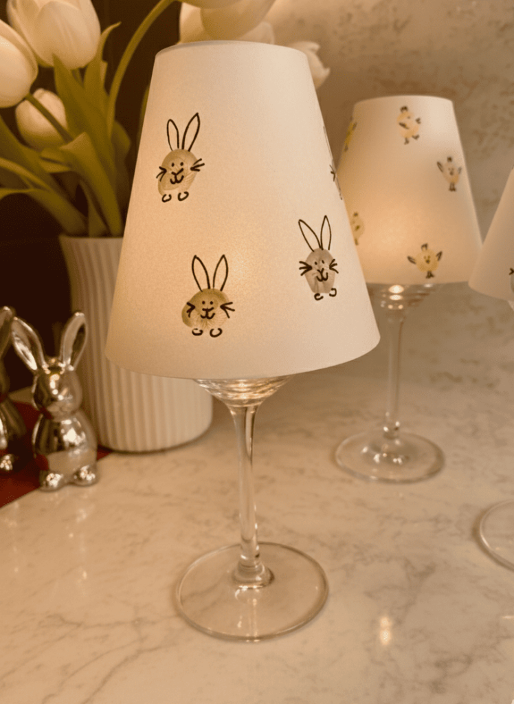 ostertischdeko-selber-machen-windlichter-tulpen.jpg Oster-Tischdeko selber machen – Windlichter aus Weingläsern mit Hasen und Küken, Tulpen im Hintergrund