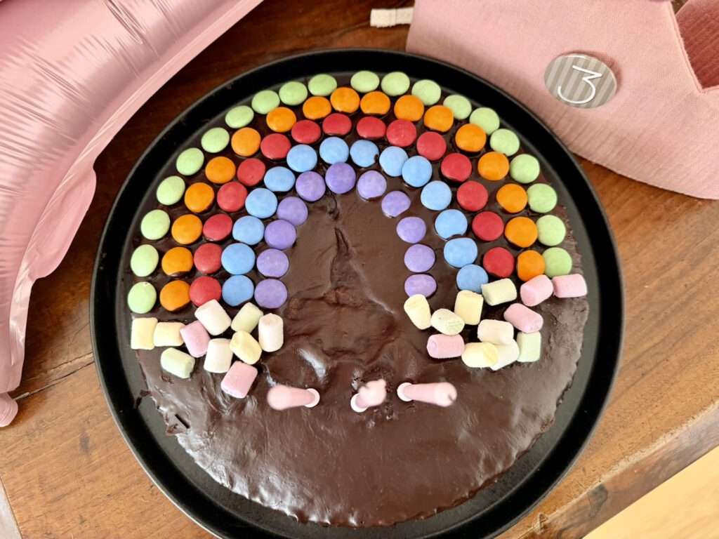 Einfacher Schokokuchen mit Schokoladenglasur und Regenbogen aus Smarties und Mini-Marshmallows