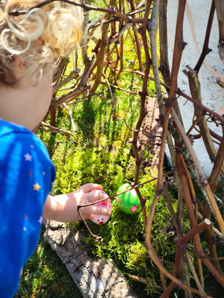 kleinkind-findet-ostereier-im-osternest Kleinkind findet bunte Ostereier in ein Osternest im Garten