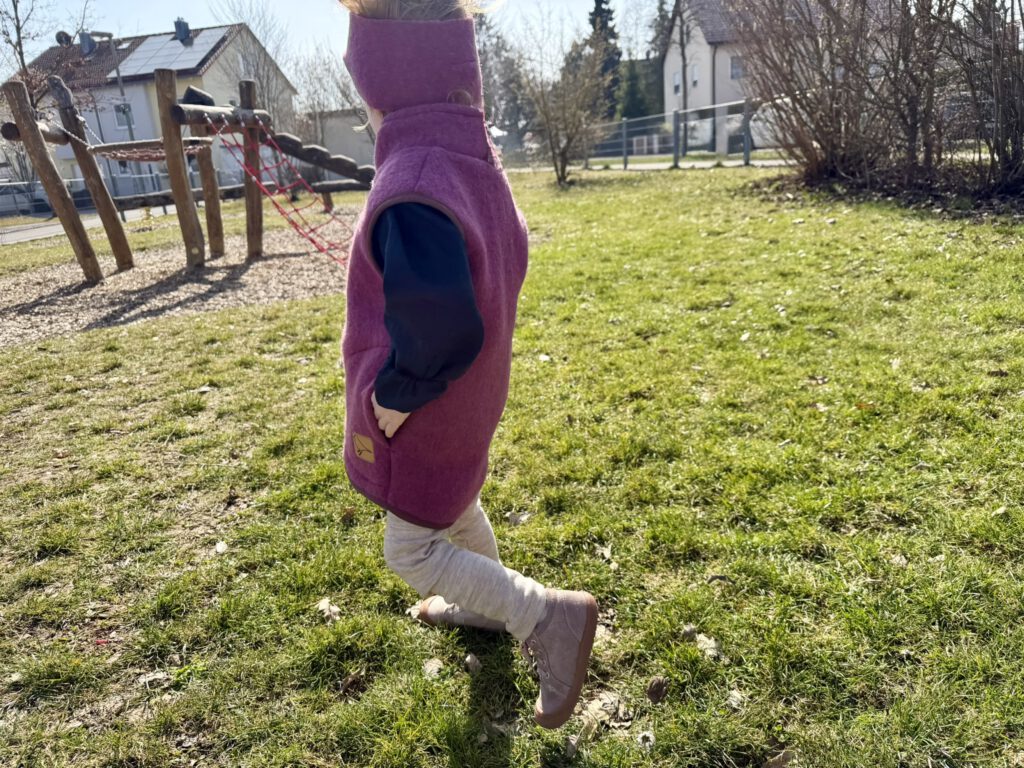 Kleinkind mit Wollfleeceweste und Stirnband aus Merinowolle im Frühlingsoutfit