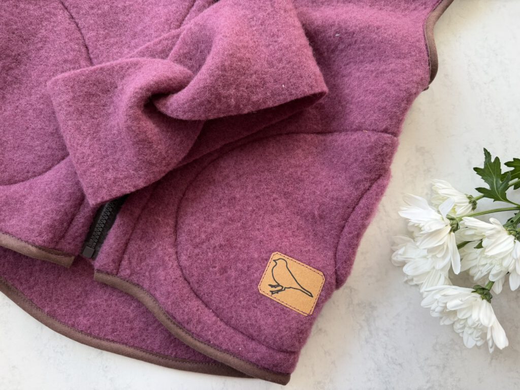 Flatlay von Wollfleeceweste und Stirnband für Kinder aus Merinowolle von Buchfinkkleidung