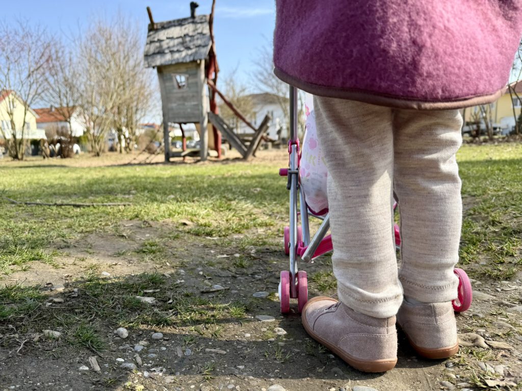 Kind von hinten auf dem Spielplatz mit warmer Wollleggings aus Merinowolle