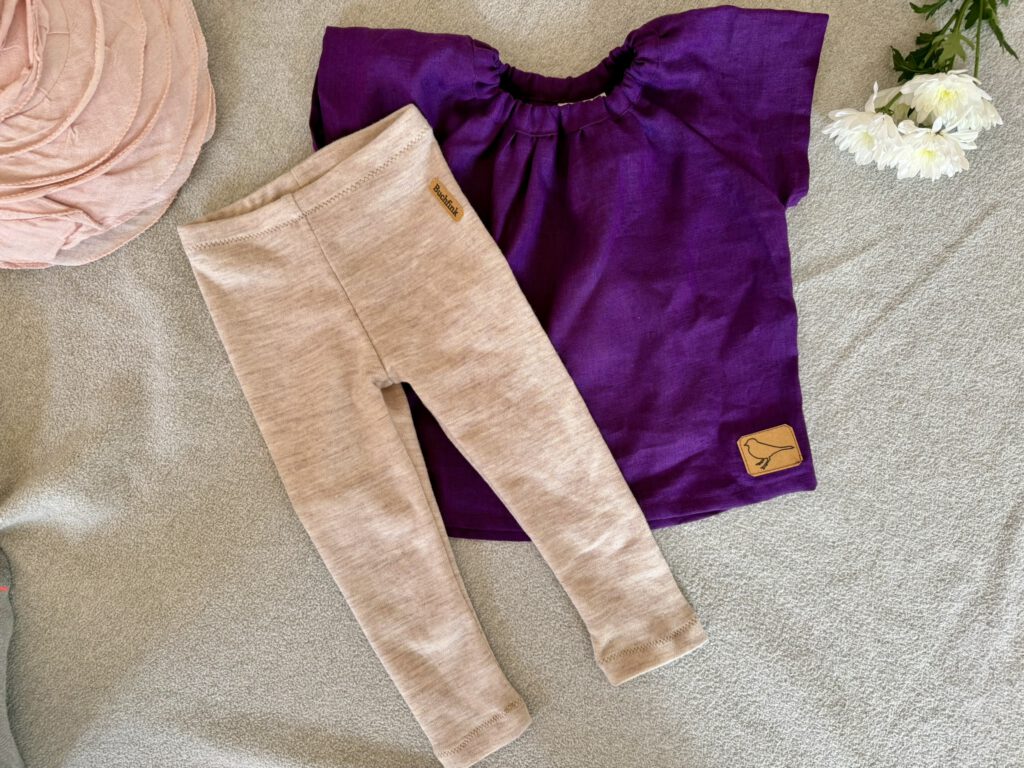 Flatlay von Wollleggings und Kurzarmbluse für Kinder aus Naturmaterialien